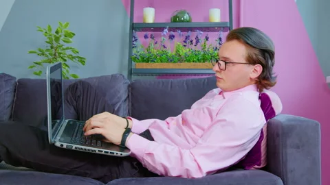 Office worker sitting on sofa, typing on laptop Video stock 235519389