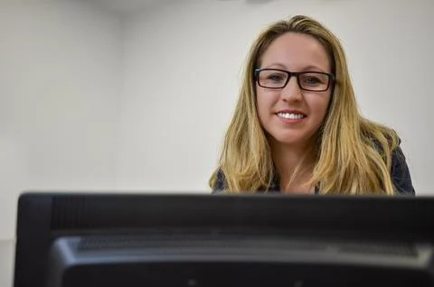 Office worker smiling while using desktop computer Stock Photos