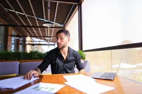 Office worker sorting papers on table near laptop. Stock Photos