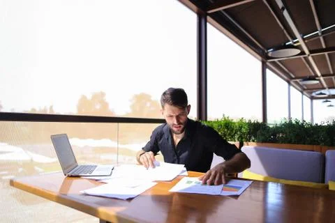 Office worker sorting papers on table near laptop. Foto stock
