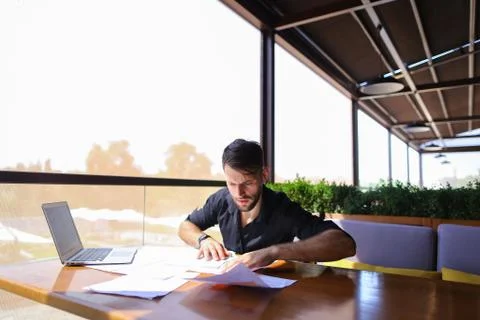 Office worker sorting papers on table near laptop. Foto stock