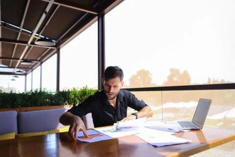 Office worker sorting papers on table near laptop. Stock Photos