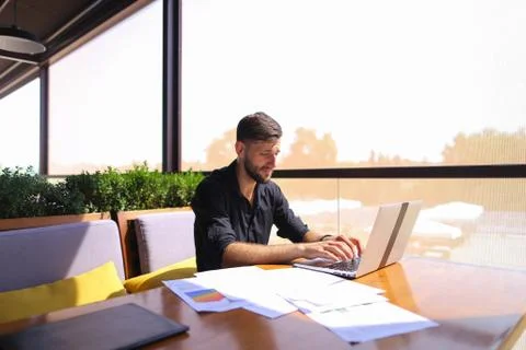 Office worker sorting papers on table near laptop. 스톡 사진