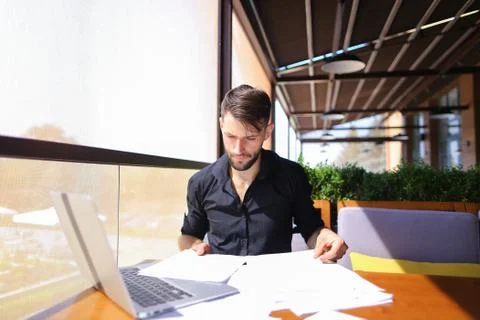 Office worker sorting papers on table near laptop. 스톡 사진