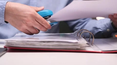 Office worker stapling documents to a folder using a blue stapler Video stock 306363801