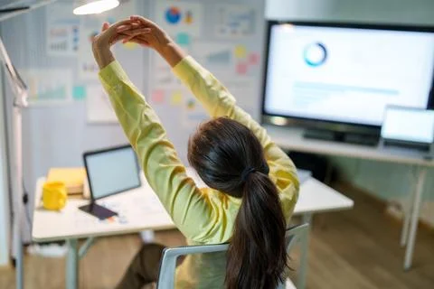 Office worker stretching at desk during work break for workplace wellness and Stock Photos