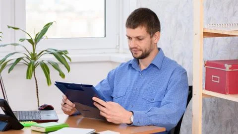 Office worker at the table reads documents in a folder Foto stock