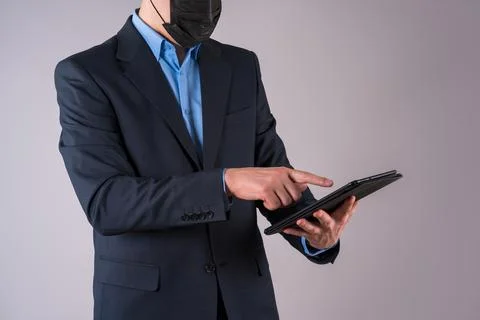Office worker with tablet in protective mask on gray background Photos