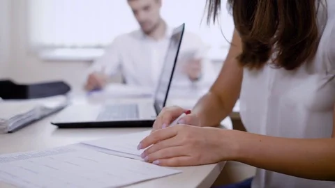 An office worker takes a folder with information from a colleague who sits at Stock Footage 82719278