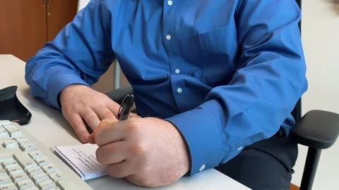 An office worker takes notes at his desk at a corporate job Stock Footage 123441400