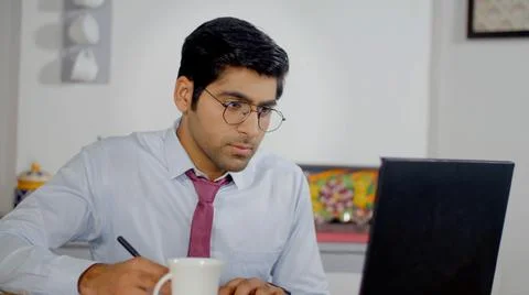 Office worker taking down notes during a virtual meeting - work from home. Stock Photos