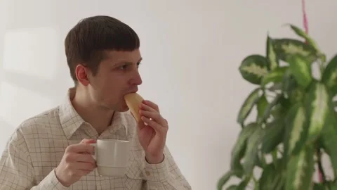 Office worker taking a lunch break eating pastry and drinking coffee Stock Footage 335143522