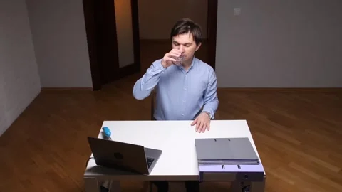 Office worker taking medicine at workplace during overtime work session Stock Footage 306549539