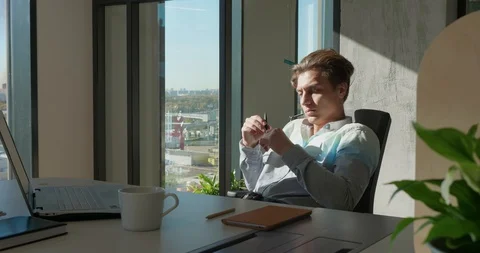 Office Worker Thinks How to Solve a Problem. He Sits At A Table And Twirls A Pen Stock Footage 129065448