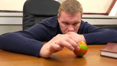 An office worker thoughtfully rolls a small ball across the table Stock Footage 100006493