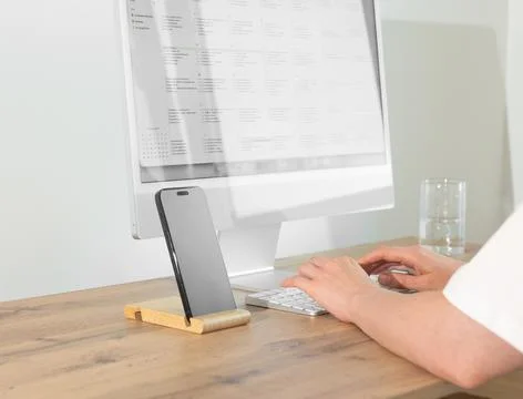 Office worker typing on computer keyboard near smartphone mockup on wooden .. Stock Photos