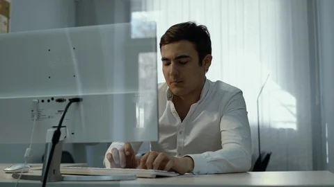 Office worker typing on keyboard. Guy thoughtfully brings his hand to his chin Video stock 111940680