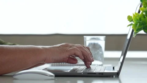 Office worker typing on laptop keyboard in bright workspace Stock Footage 316149553