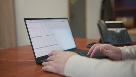 Office worker typing on laptop keyboard and answering phone 스톡 동영상 332336603