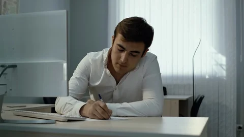 Office worker typing on wireless keyboard and writes with pen in notebook Video stock 111944684