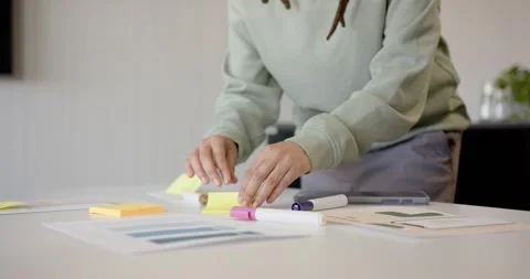Office worker is uncapping marker, placing sticky notes on chart on white table Stock Footage 344673376
