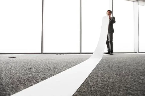 Office worker unrolling long sheet Stock Photos