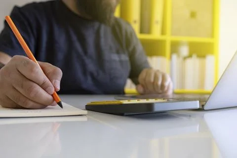 Office worker using laptop and taking notes. Close up image, copy space. Stock Photos