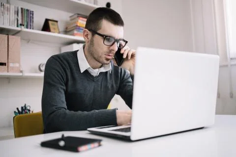 Office worker using laptop while speaking on phone Stock Photos