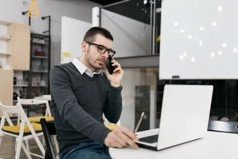 Office worker using laptop while talking on phone Foto stock