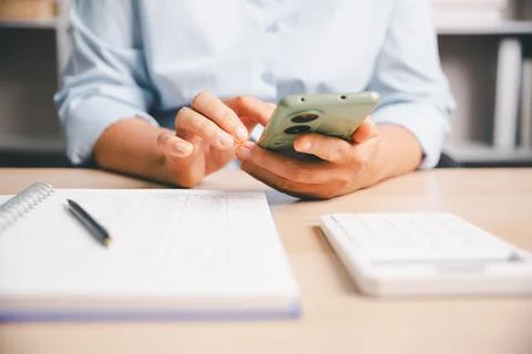 Office worker using smartphone calculator to compute financial numbers at d.. Stock Photos