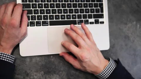 Office worker is working on his laptop, typing on keyboard and using trackpad Stock Footage 295013343