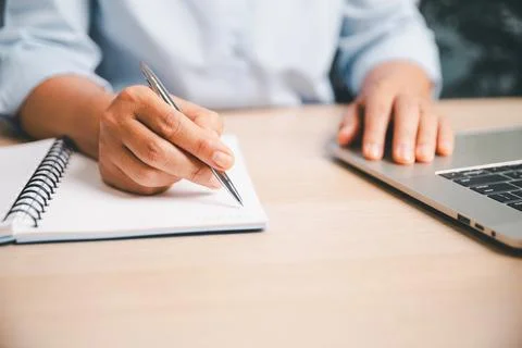 Office worker writing notes in a notebook while using a laptop, illustratin.. Stock Photos