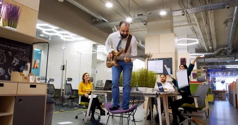 Office workers are having fun, a man is playing guitar, people throw paper, 4k Stock Footage 129322884
