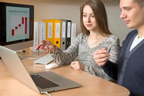 Office workers discuss the task sitting at the desk and gesturing Stock Photos