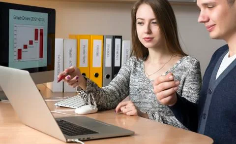 Office workers discuss the task sitting at the desk and gesturing Stock Photos