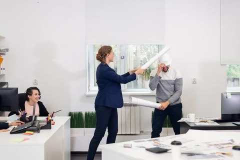 Office workers fooling in the studio, fighting with improvised s Stock Photos