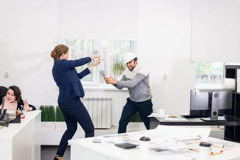 Office workers fooling in the studio, fighting with improvised s Stock Photos
