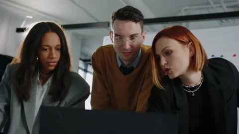 Office workers in front of a laptop discussing plans for the month Stock Footage 232476871