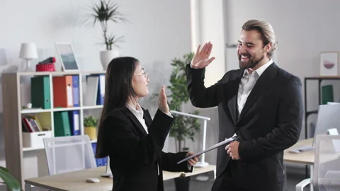 Office workers giving high five while standing in office Stock Footage 202122150