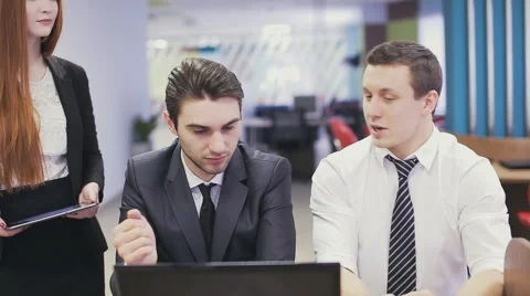 Office workers looking at laptop and discussing Stock Footage 63224272