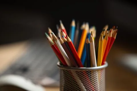 Office workplace. Focus on multi-colored pencils in foreground at wooden table Stock Photos