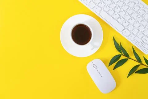 Office workplace with keyboard, computer mouse, cup of coffee and plant on ye Stock Photos