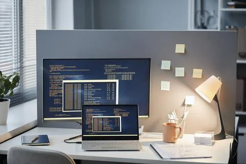 Office Workplace Setting with Code Lines on Computer Screens Foto stock