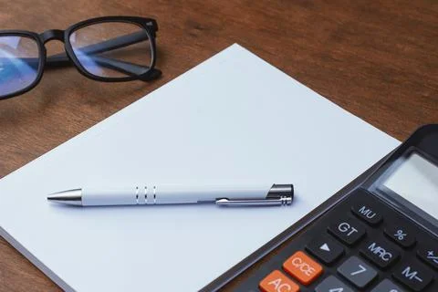 Office workspace featuring a black calculator, white pen, and mockup magazine Stock Photos