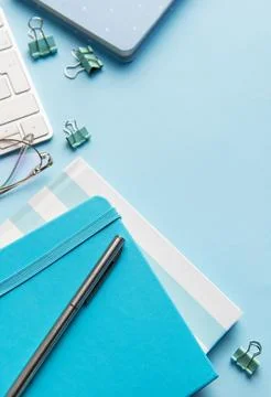 Office workspace with keyboard, notebooks, and blue supplies Stock Photos