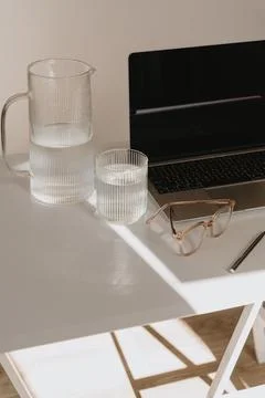 Office workspace table with laptop computer, decanter, glass of pure water, g Stock Photos