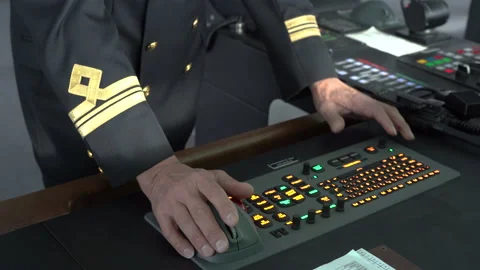 Officer at control panel inside bridge. Mate with portable radio in hand presses Stock Footage 230700414