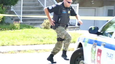 Officer running in peaceful neighborhood with hand on his gun Stock Footage