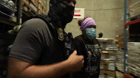 Officers apprehend an unauthorized worker hiding in factory storage shelving Stock Footage 334177014