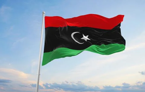 Official flag of Libya at cloudy sky background on sunset, panoramic view. pa Stock Illustration